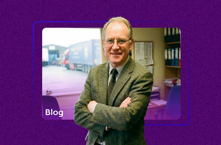 Gráfico de capa para um blog, com a palavra "Blog" sobreposta à foto do homem no escritório com vista para caminhões. O tema é contabilidade para transportadora.