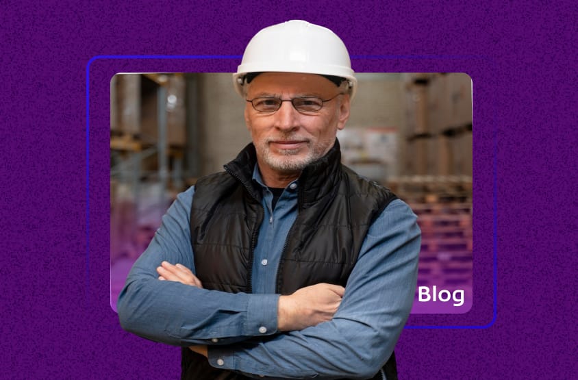 Homem de meia-idade com capacete branco e óculos, de braços cruzados em um depósito de materiais de construção, ilustrando um artigo de blog sobre Nota Fiscal de Material de Construção.